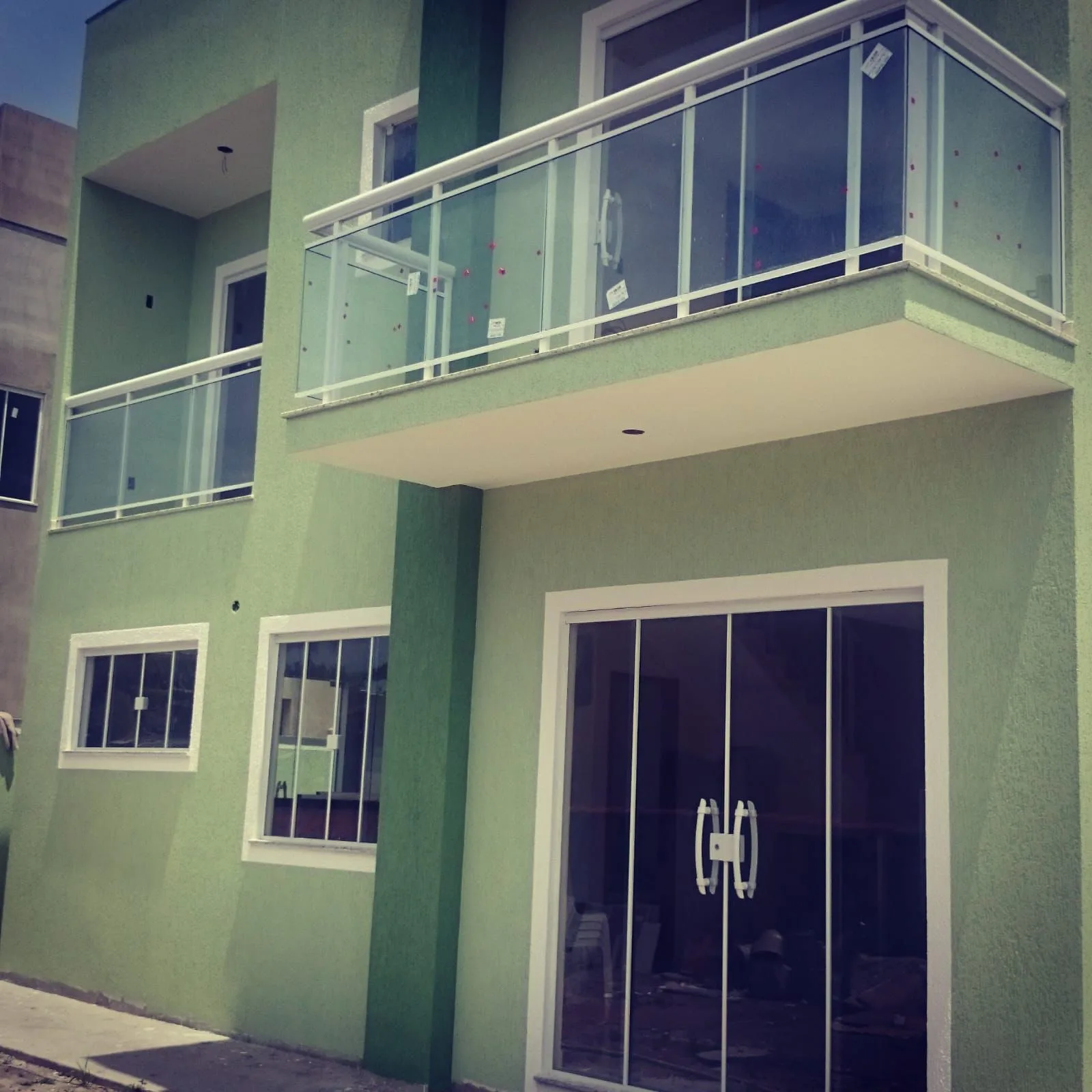 Fachada com sacada envidraçada e gradil verde